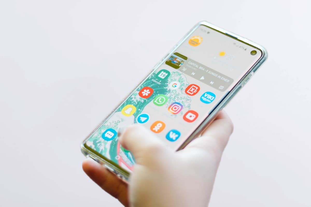Hand holding a smartphone displaying a smart home control dashboard